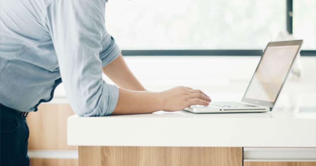 Ergonomia em um ambiente corporativo: homem utiliza computador sobre bancada planejada.